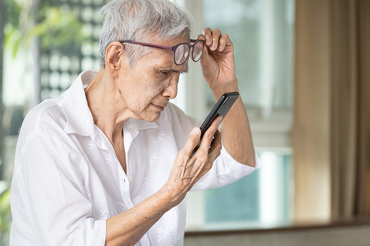 Asian senior woman with eye glasses,try to read messages